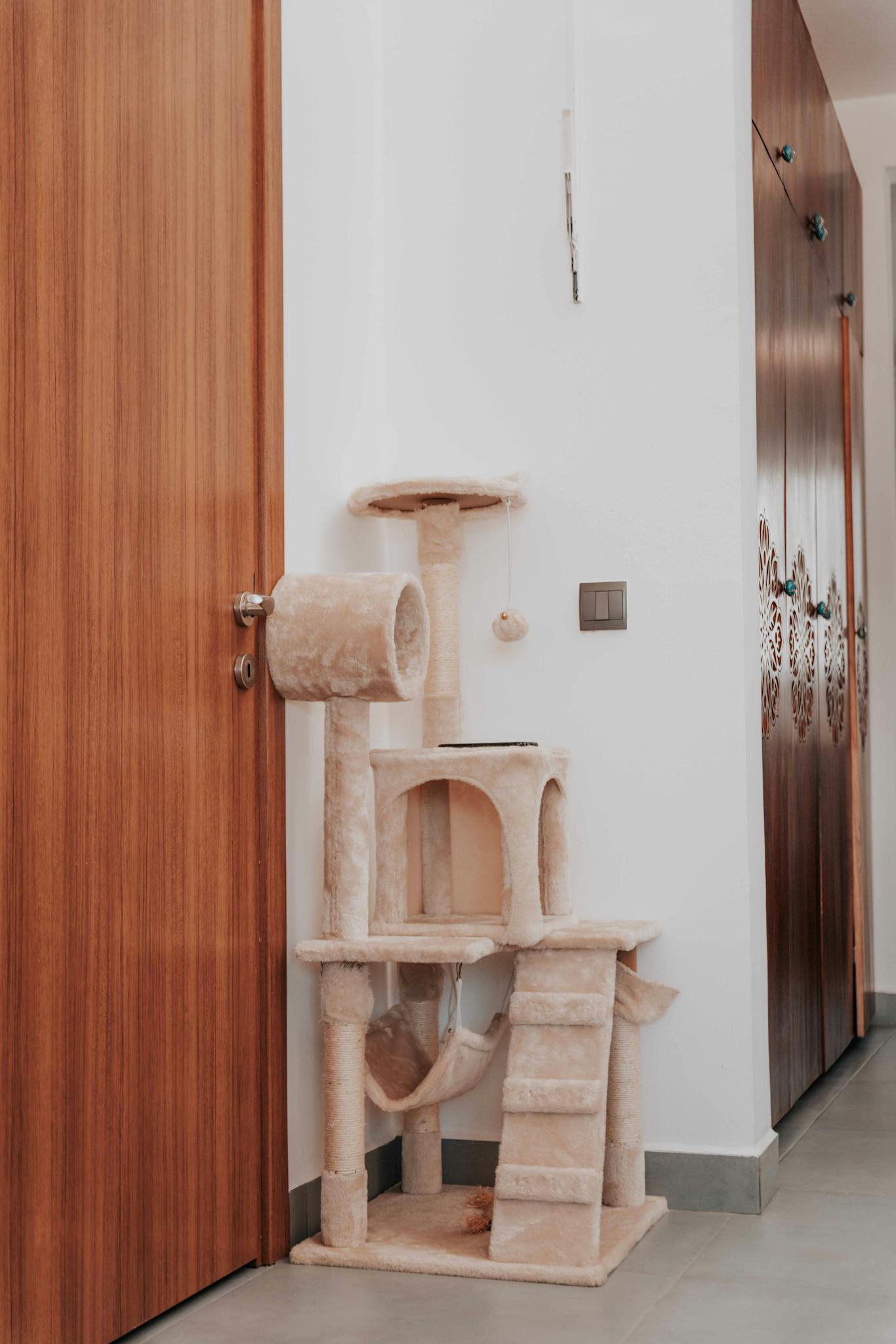 Modern indoor setup featuring a plush cat tree next to a wooden door, ideal for pet lovers.